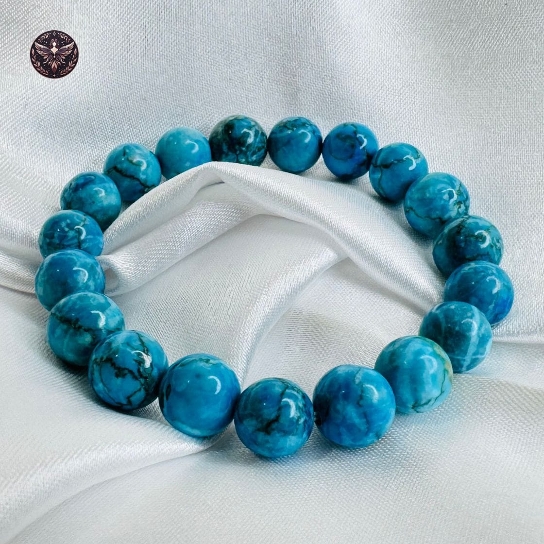 Turquoise crystal bracelet with polished round beads displayed on white satin fabric