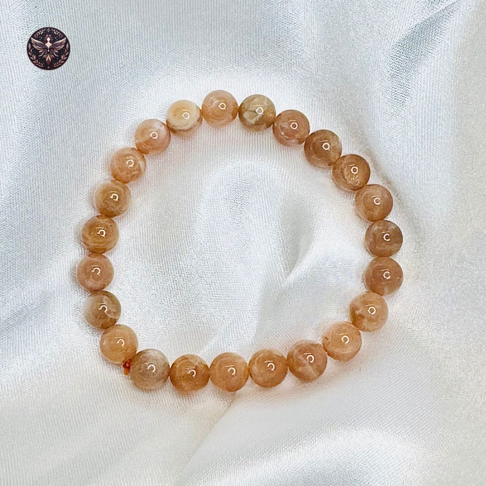 Sunstone crystal bracelet with polished peach-golden beads displayed on white satin