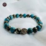 Pyrite and Turquoise Opportunity Magnet Bracelet with charm displayed on white satin background