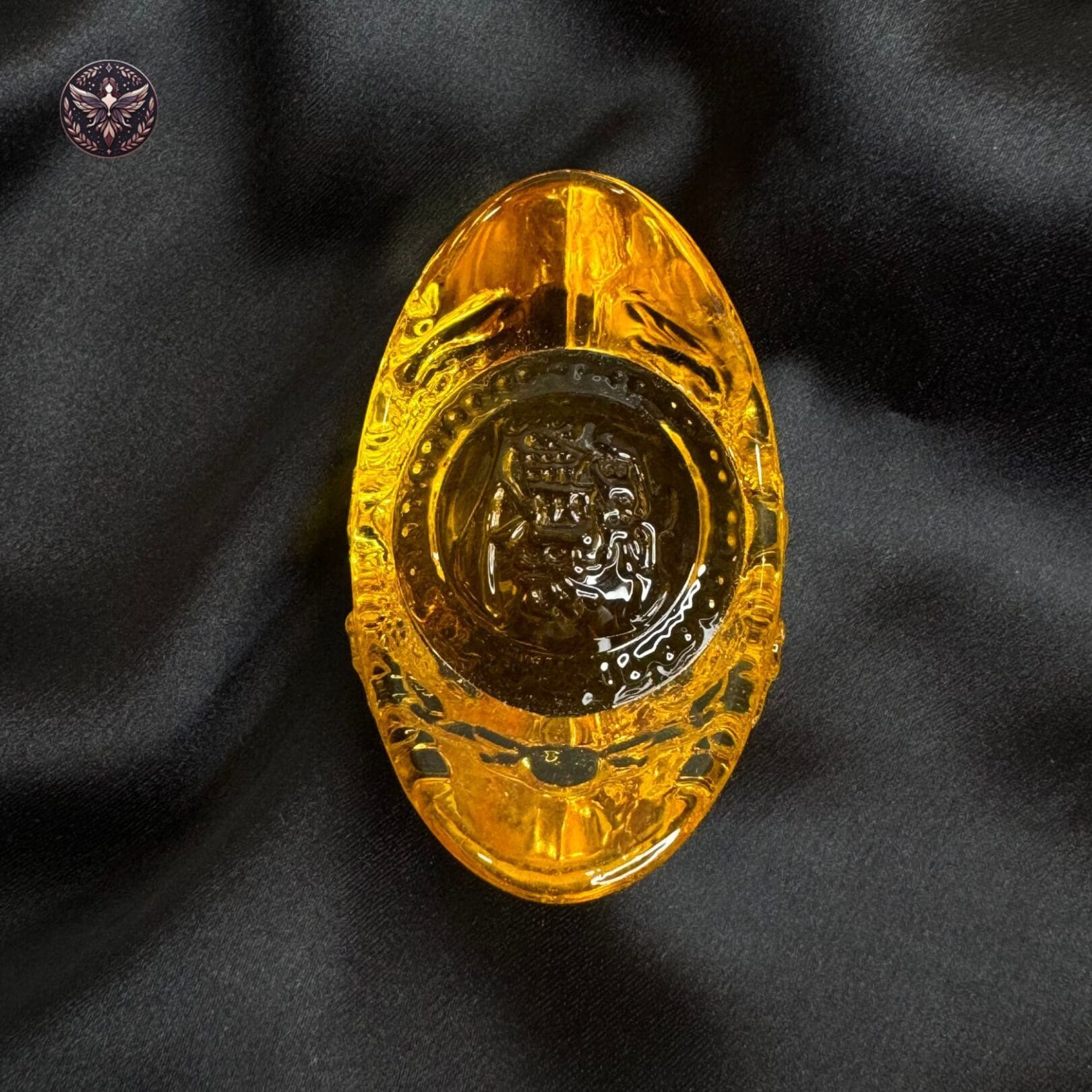 Golden Feng Shui wealth ingot placed on black satin cloth